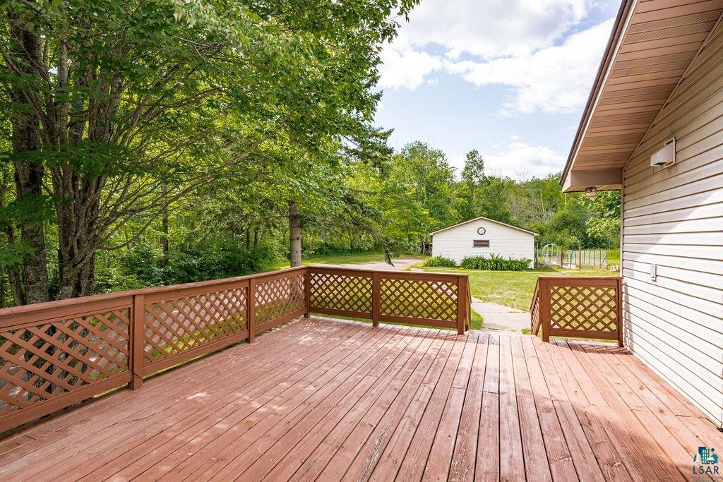 5025 Reid Road Duluth, MN 55803 - Photo 7 of 51 Expansive wood deck with lattice railing, offering views of a detached structure and mature trees