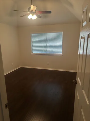 a view of a livingroom with wooden floor a ceiling fan and a window