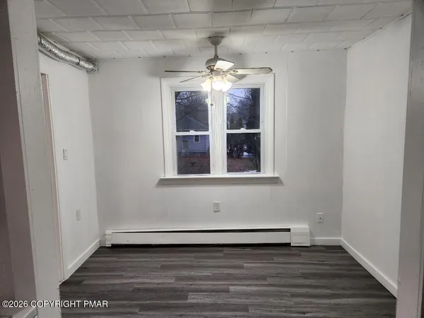 a view of an empty room with wooden floor and a window