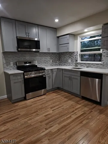 a kitchen with stainless steel appliances granite countertop a stove a sink and a microwave