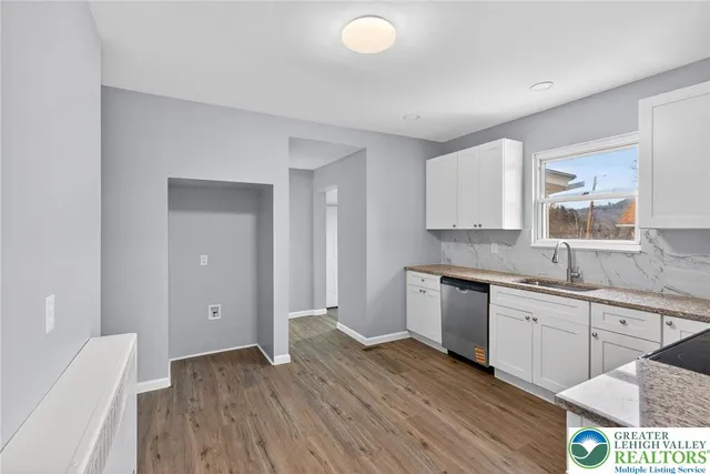 a view of a kitchen with a sink wooden cabinets and entryway