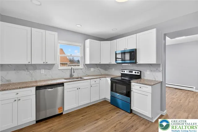 a kitchen with granite countertop white cabinets and black stainless steel appliances