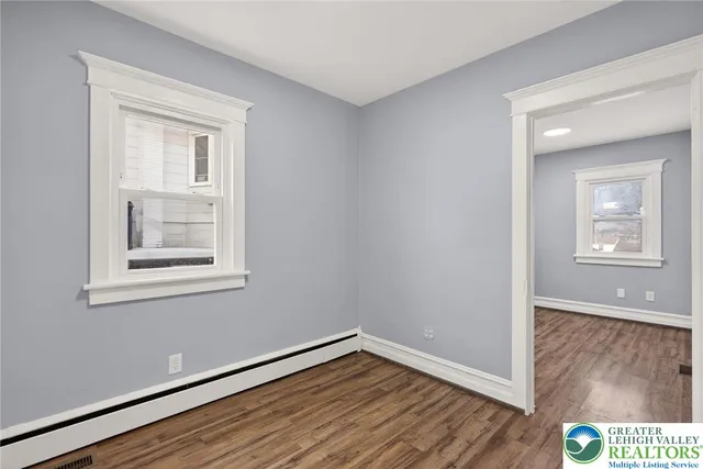 a view of an empty room with wooden floor and a window