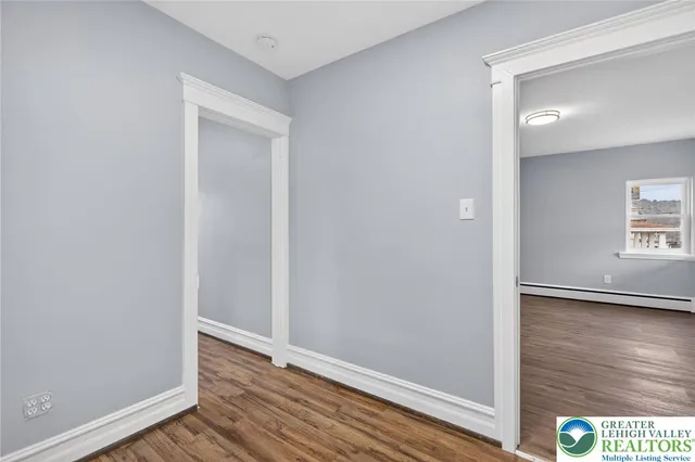 a view of hallway with window and wooden floor