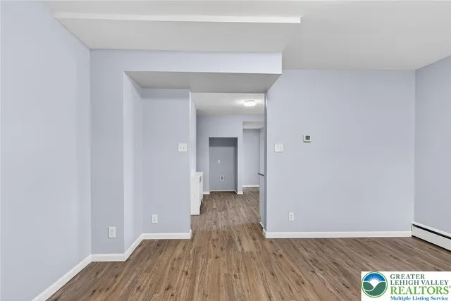 a view of a hallway with wooden floor and a bathroom