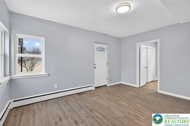 an empty room with wooden floor and windows