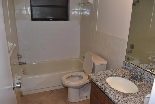 a bathroom with a granite countertop toilet sink and mirror