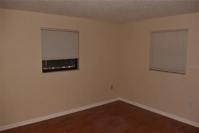 an empty room with a wooden floor and mirror