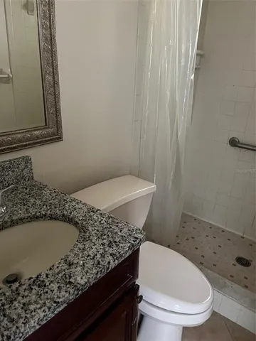 a bathroom with a granite countertop toilet and a sink