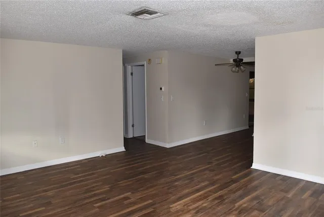 an empty room with wooden floor and a ceiling fan