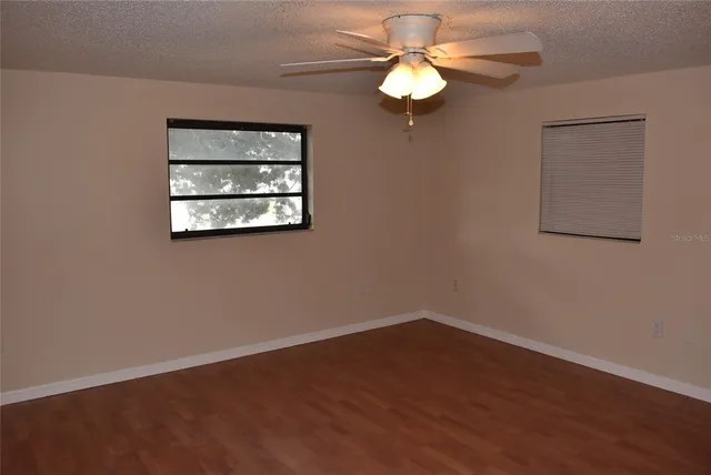 a view of a room with a large window ceiling fan and wooden floor