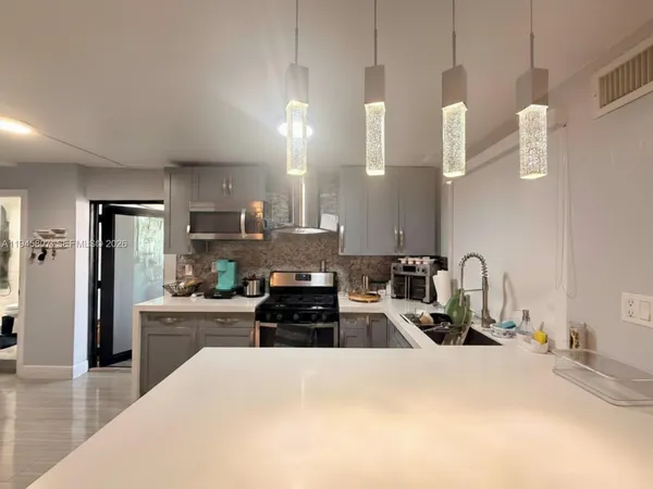 a kitchen with granite countertop a refrigerator stove top oven and sink