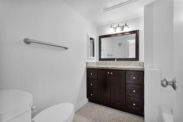a bathroom with a granite countertop sink a mirror and a toilet