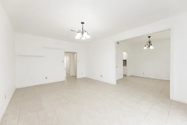 an empty room with a chandelier fan and windows