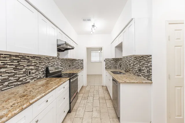 a kitchen with granite countertop a sink and a stove