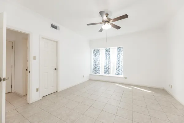 an empty room with windows and fan