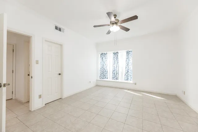 an empty room with windows and fan