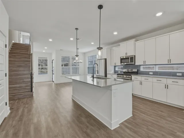 a kitchen with stainless steel appliances granite countertop a sink stove oven and white cabinets with wooden floor