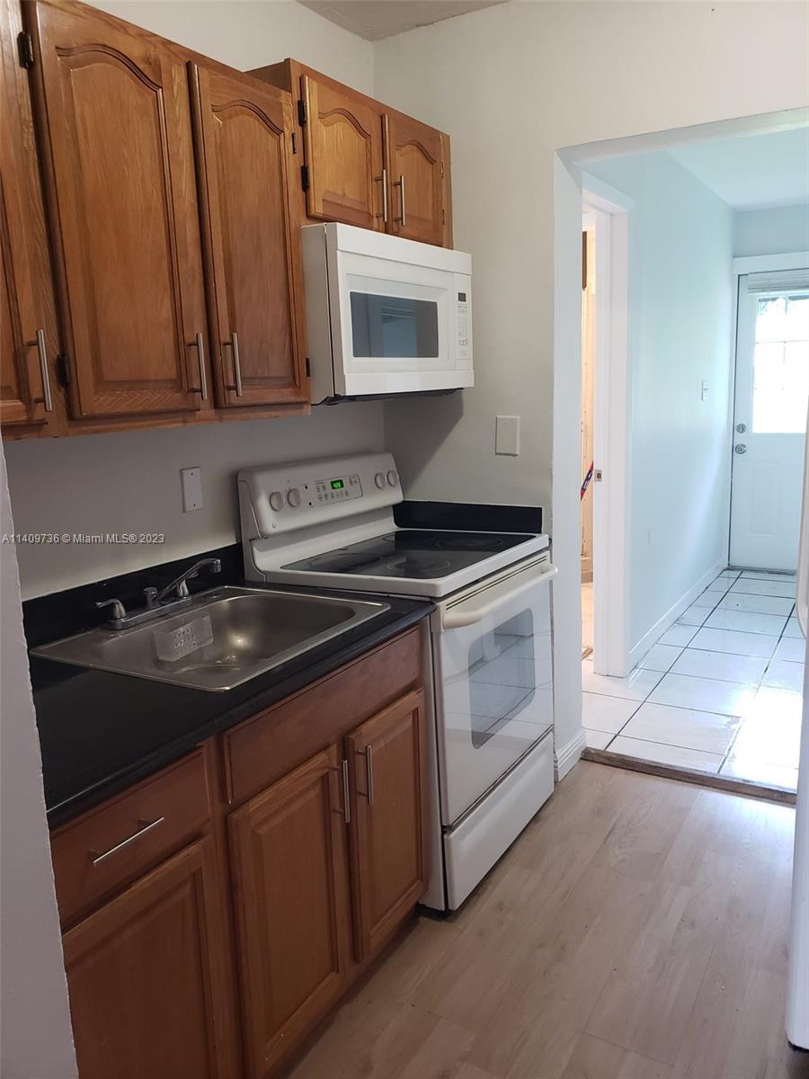2940 Southwest 38th Court, Unit 2942 Miami, FL 33134 - Photo 5 of 10 a kitchen with stainless steel appliances granite countertop a sink stove and microwave