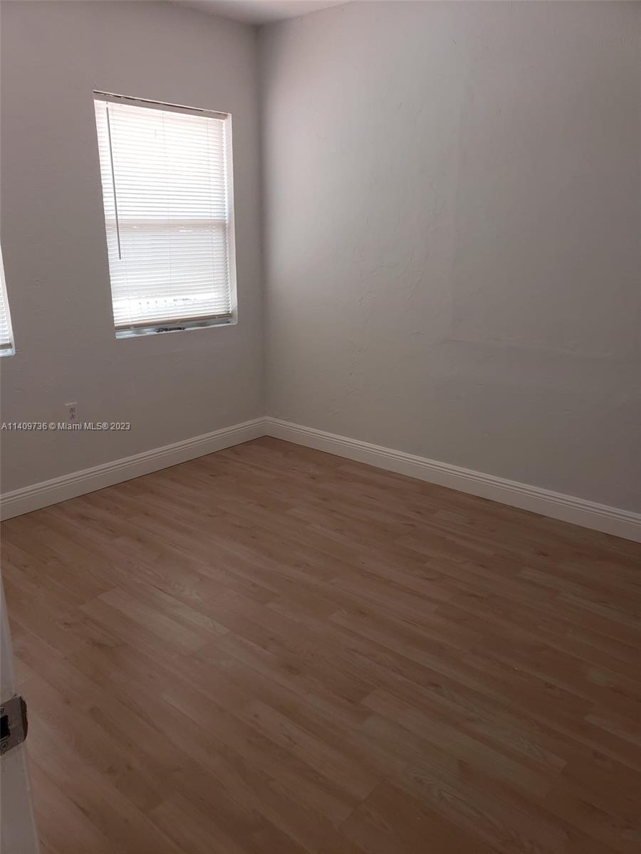 2940 Southwest 38th Court, Unit 2942 Miami, FL 33134 - Photo 6 of 10 an empty room with wooden floor and windows