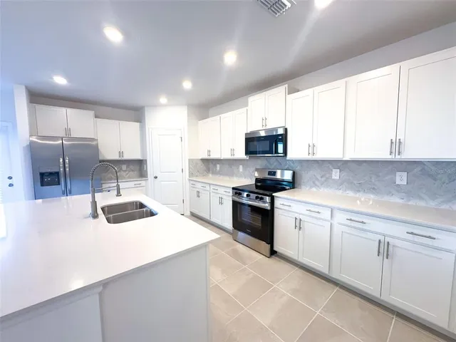 a kitchen with kitchen island white cabinets appliances and a window