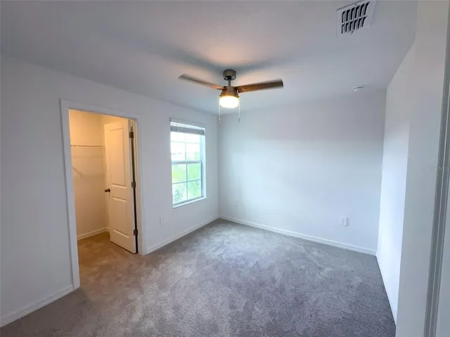 an empty room with windows and a ceiling fan