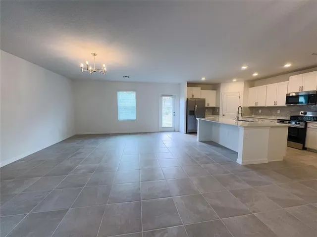 a view of a kitchen with kitchen island a sink wooden floor and stainless steel appliances