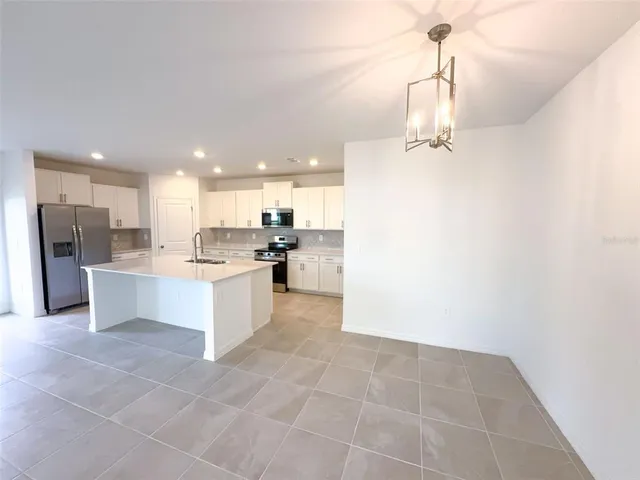 a large kitchen with a large counter top a refrigerator and cabinets