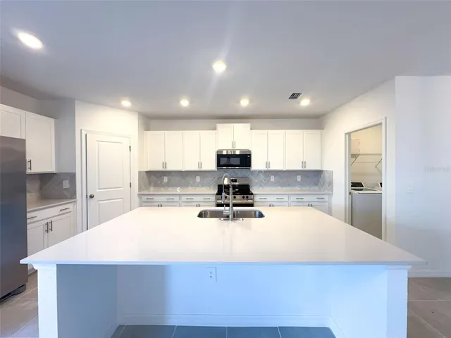 a kitchen with kitchen island a counter top space a sink stainless steel appliances and cabinets