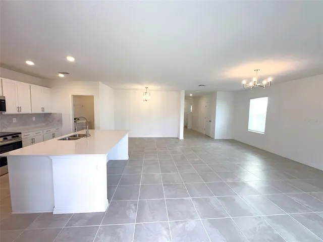 a large white kitchen with kitchen island a sink a stove and a refrigerator