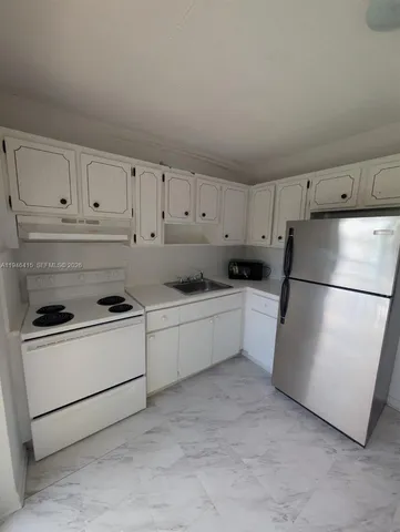 a kitchen with stainless steel appliances granite countertop white refrigerator stove a white sink and white cabinets