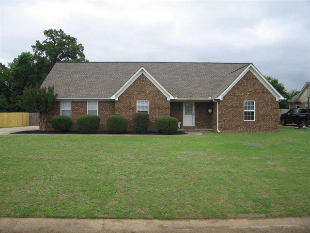 a view of a house with a big yard potted plants and large tree