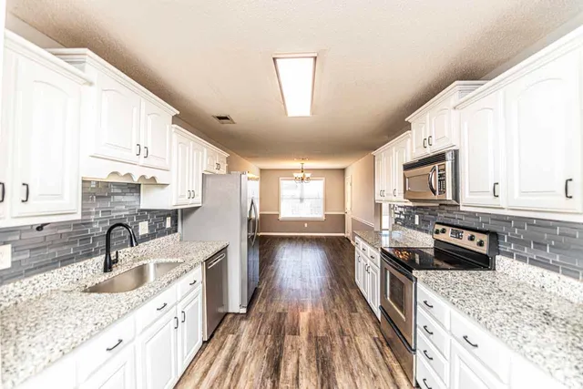 a kitchen with stainless steel appliances granite countertop a sink stove and refrigerator