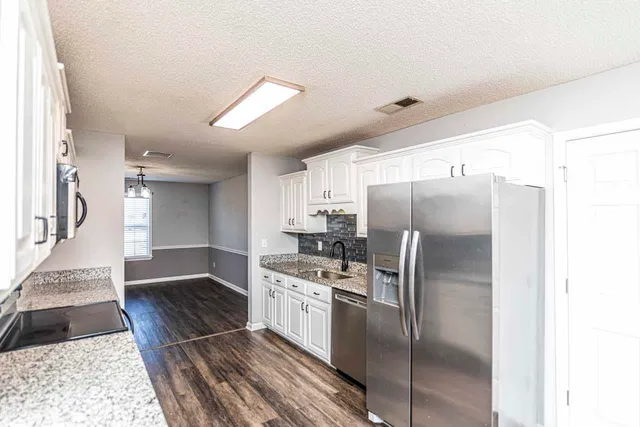 a kitchen with stainless steel appliances granite countertop a refrigerator and a stove