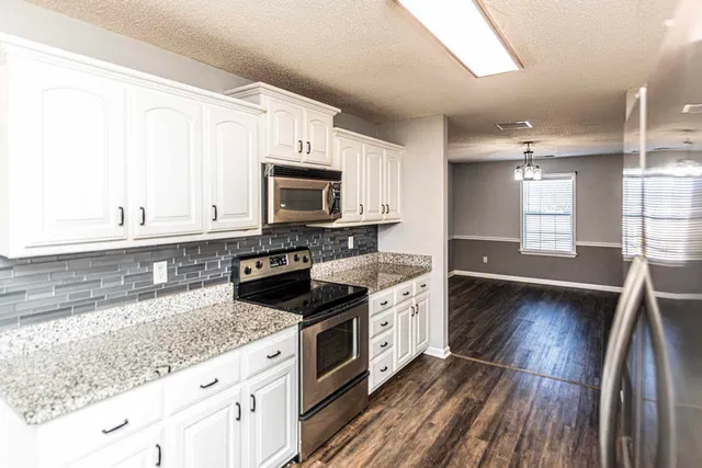 a kitchen with stainless steel appliances granite countertop a stove a sink and a microwave