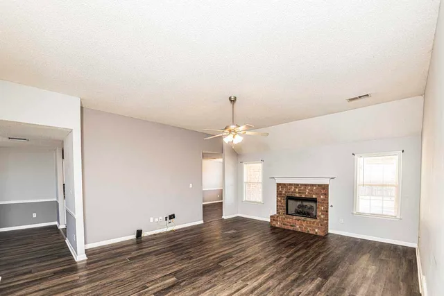 an empty room with wooden floor fireplace and window