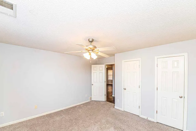 an empty room with a ceiling fan and a window