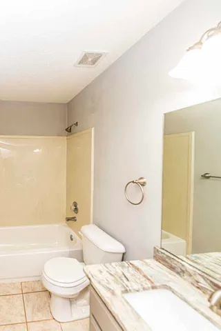 a bathroom with a granite countertop sink toilet mirror vanity and shower
