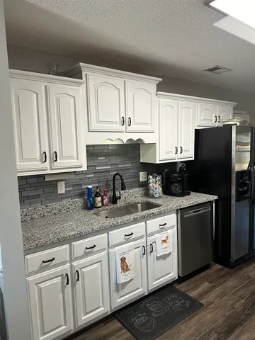a kitchen with granite countertop white cabinets white stainless steel appliances and sink