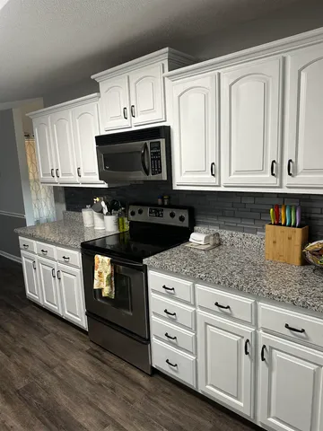 a kitchen with granite countertop white cabinets and black appliances