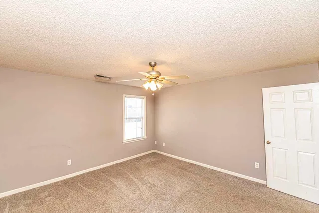 an empty room with windows and fan