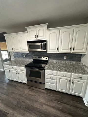 a kitchen with stainless steel appliances granite countertop a stove a microwave and a white cabinets
