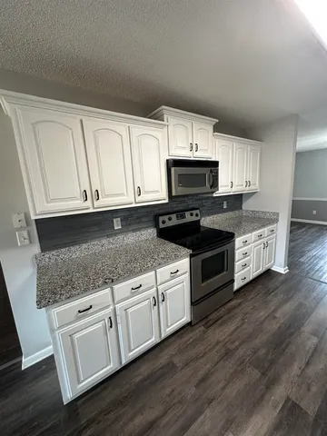 a kitchen with white cabinets a sink and wooden floor