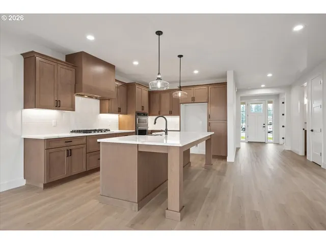 a view of an empty room with a window and kitchen view