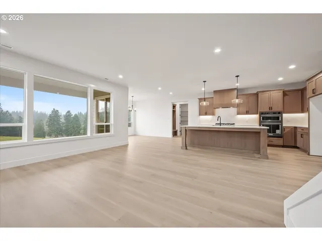 a large white kitchen with a stove a sink a kitchen island with wooden cabinets and floors