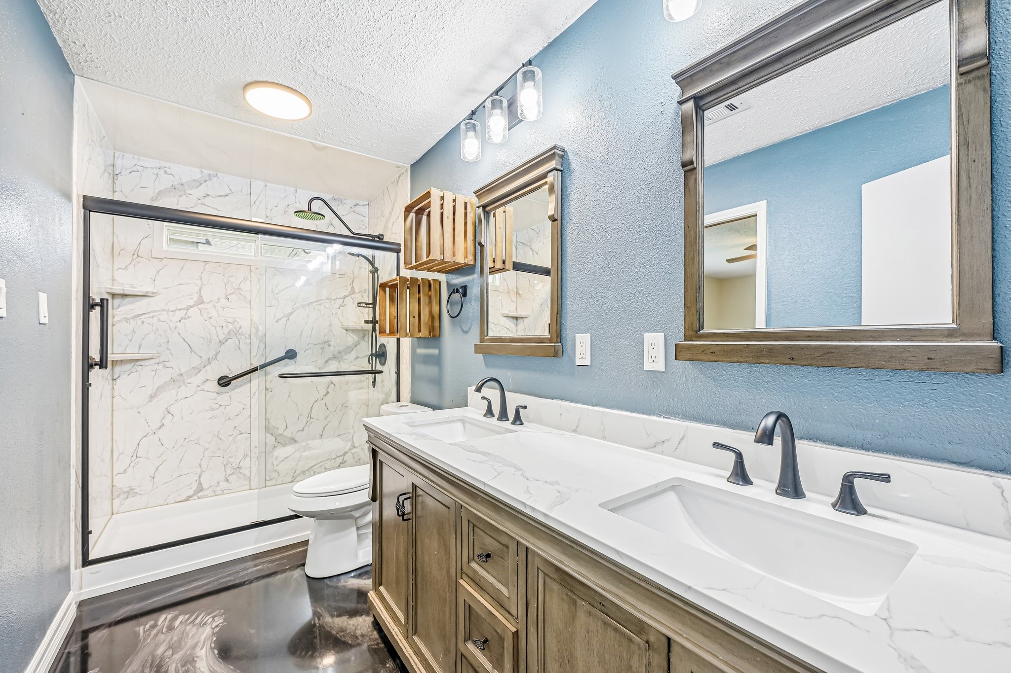 8 Arlington Street Conroe, TX 77301 - Photo 21 of 37 This modern bathroom features a spacious double vanity with sleek fixtures, elegant marble countertops, and a large walk-in shower with a glass door. The walls are painted a soothing blue, complemented by stylish wood-framed mirrors and chic lighting.