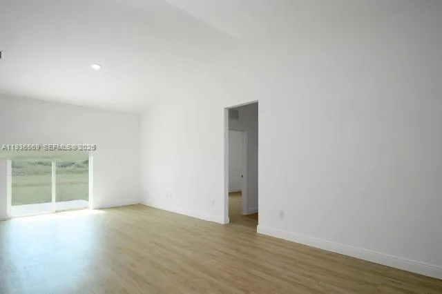 an empty room with wooden floor and window