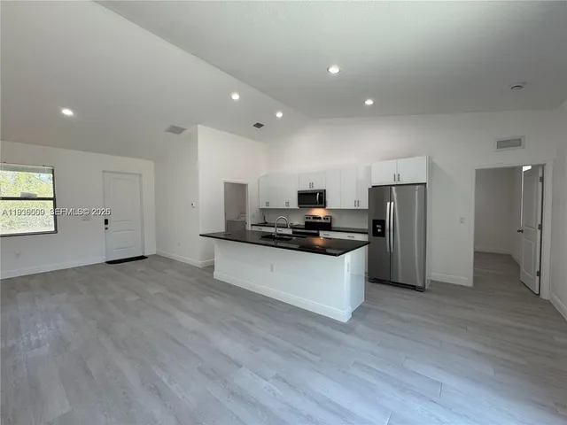 a kitchen with stainless steel appliances kitchen island granite countertop a refrigerator and a stove