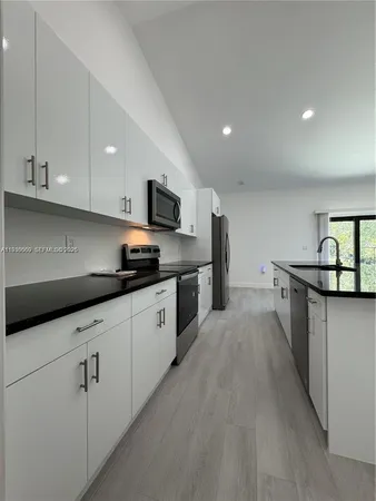a kitchen with stainless steel appliances a sink dishwasher stove refrigerator and cabinets