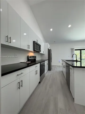 a kitchen with stainless steel appliances a sink dishwasher stove refrigerator and cabinets